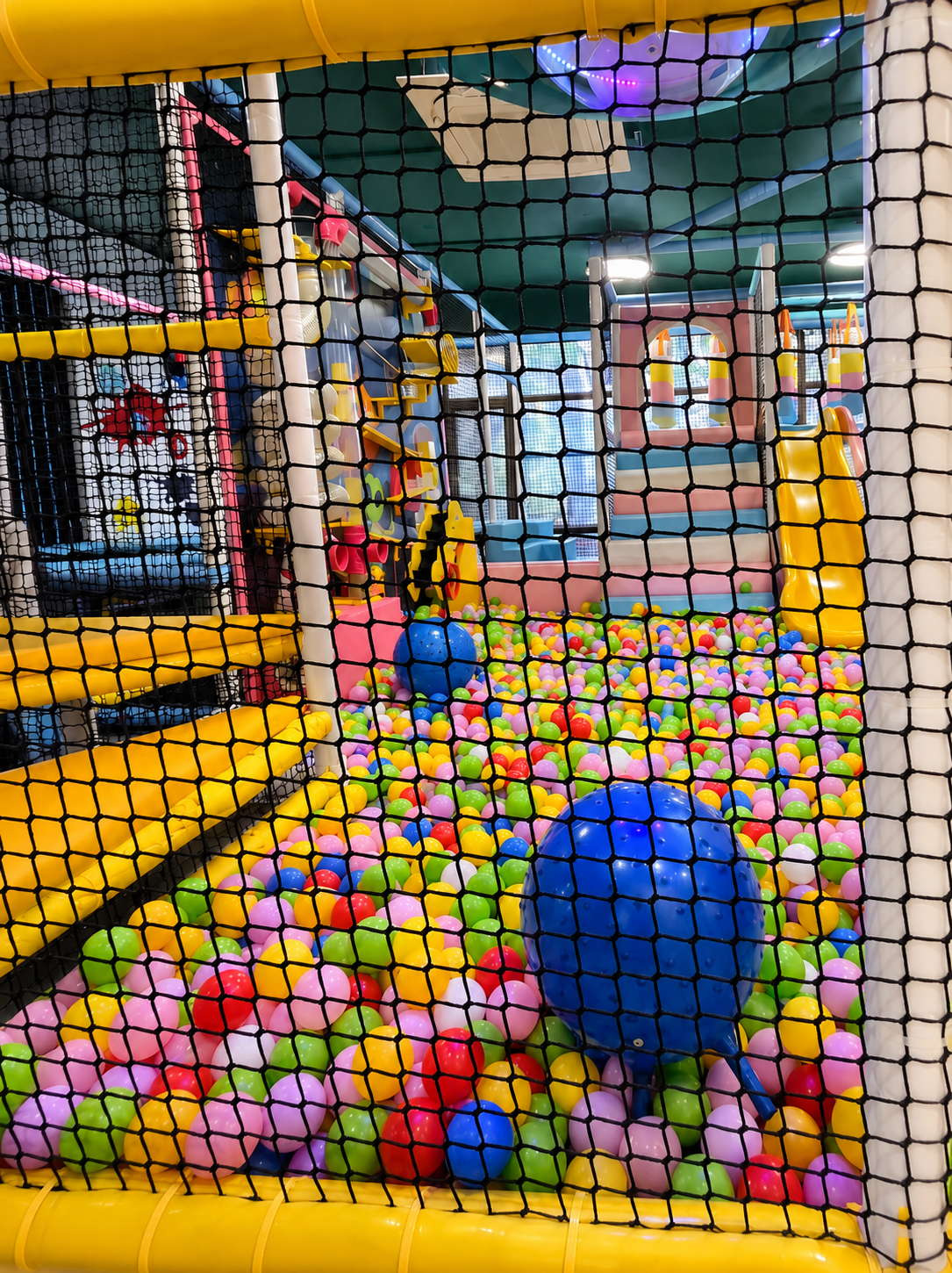 Giant indoor ball pit in Delhi with thousands of colourful balls, bouncy balls and a yellow tube slide entry behind safety netting